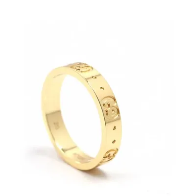 A gold band ring with small engraved marks, photographed alone on white